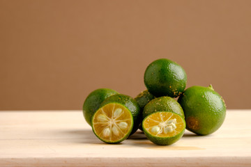 Calamansi on wooden table and brown background