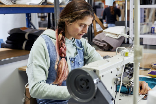 Female Worker Stitching Textile In Sofa Workshop