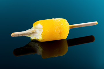 studio shoot yellow popsicle on a blue background with some bites