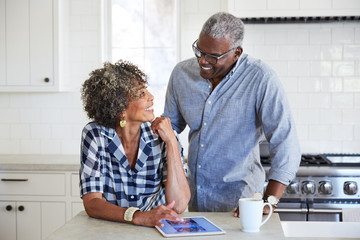 African American Senior Couple looking at cell phone in the kitchen together