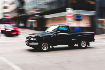 Panning shot of pickup traveling down a city street