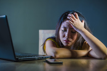 dramatic portrait scared and stressed Asian Korean teen girl or young woman with laptop computer...