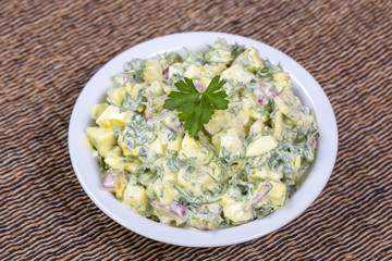 Salad of radish, boiled egg, parsley and sour cream in white bowl - healthy breakfast concept
