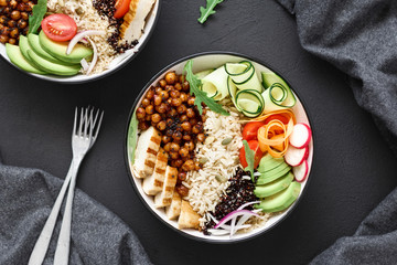 Two buddha bowl Clean balanced healthy food concept Chicken grilled steak rice spicy chickpeas black white quinoa avocado carrot zucchini radish tomatoes dark background top view