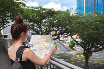 Naklejka na ściany i meble Young asian woman traveler holding map to find direction in Singapore