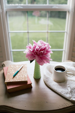 vertical image of a journal, book, coffee, and flower on a desk