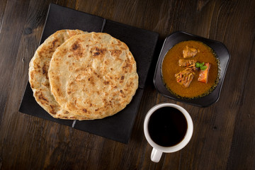 Roti Parata or Roti canai with chicken curry sauce, popular Malaysian breakfast.