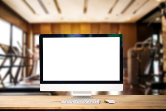 Computer Monitor, Keyboard,coffee cup and Mouse with Blank or White Screen Isolated is on the work table at the fitness gym in morning light