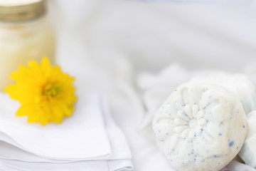  Handmade soaps on the white material, yellow flower near it,cleanliness and hygiene concept