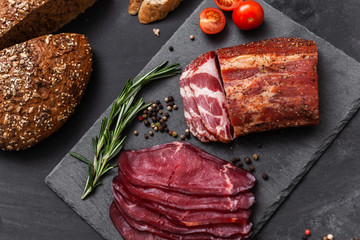 Smoked meat with ingredients on the black stone board