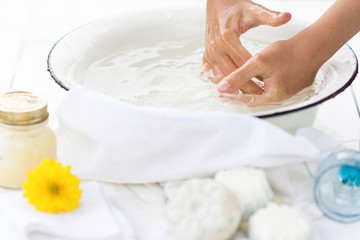 Child washes his hands in the white bowl , nearby are handmade soaps, flower and cream, cleanliness and hygiene concept