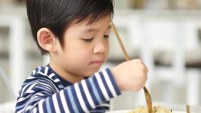 Cute Asian child eating breakfast in a restaurant 