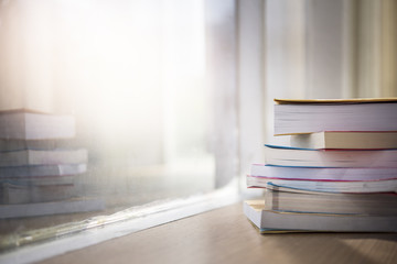 Stack of books near the window. Education background. Back to school. Book, hardback colorful books on wooden table. Education business concept. Copy space for text