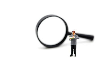 Miniature people : businessman reading a book with Magnifying glass.