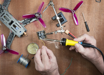 assembly of a quadrocopter assembly of parts on a wooden table using various tools