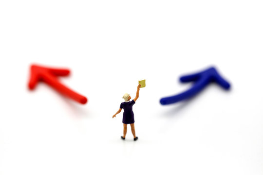 Miniature people : women reading a book with arrow.