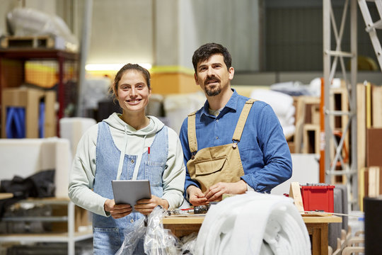 Confident Colleagues Standing At Sofa Workshop