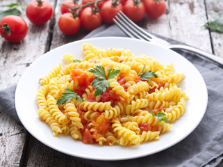 Pasta fusilli with tomatoes with parsley on a old rustic gray wooden background, low-calorie diet,...