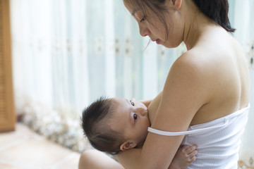 Young asian mother breastfeeding her baby boy in home