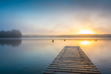 Fototapeta premium Sonnenaufgang am See mit Steg im Nebel
