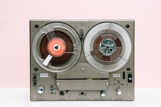 Vintage reel to reel in front of a pink background