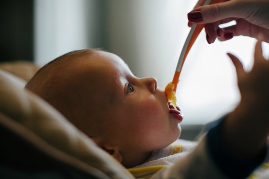 Closeup profile portrait of baby boy eating from spoon