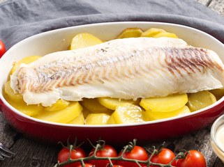 Fish cod baked in the oven with potatoes, diet healthy food. Dark old wooden rustic gray background, side view