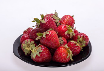 fresh ripe strawberries on black plate isolated on white background