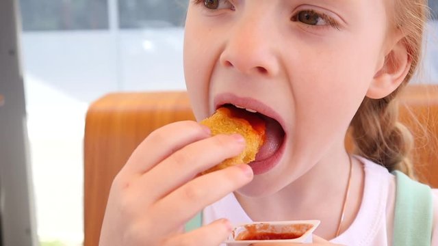 Cute Little Kid Girl Face Portrait Eating Chicken Nuggets With Ketchup In Fast Food Restaurant