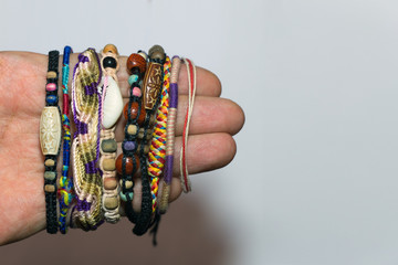 a large variety of homemade baubles ( fandangle , Sequin bracelet , friendship bracelets )  worn on hand on a gray background