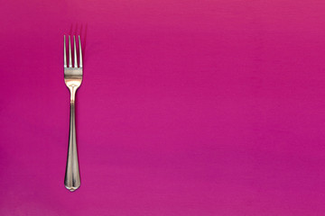 Fork on purple background. Copy space for your inscriptions. concept.