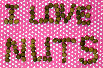Pattern with hazelnut. Abstract background. The inscription I LOVE NUTS is made with nuts on the pink background with little hearts
