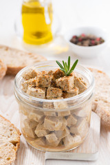marinated feta in a glass jar on a wooden board, vertical