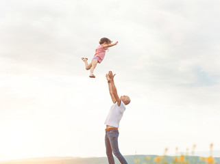 Obraz premium Father playing with his daughter in sunny field