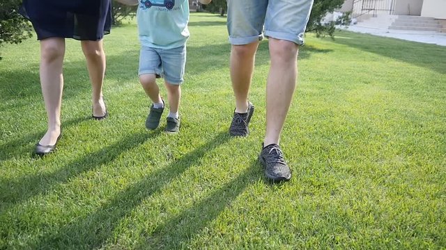 Family have fun playing on backyard, legs running on a green lawn slow motion