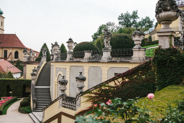 Obraz premium A medieval staircase in a garden or park next to the traditional houses of planted plants in Prague in the Czech Republic. Traditional Czech architecture