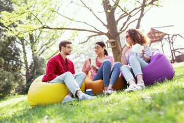Fototapeta premium Our work. Concentrated pretty woman sitting in the open air with her co-workers and discussing their project