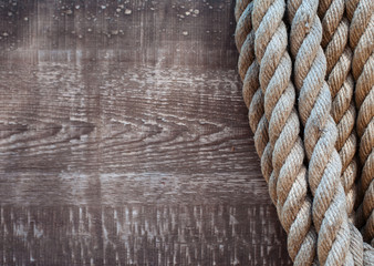 Thick rope on a background of old wooden boards in grunge style. The concept. Old American cowboy, ranch, lasso. Background for design