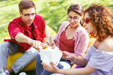 Serious work. Serious concentrated man sitting in the open air with his co-workers and discussing their project
