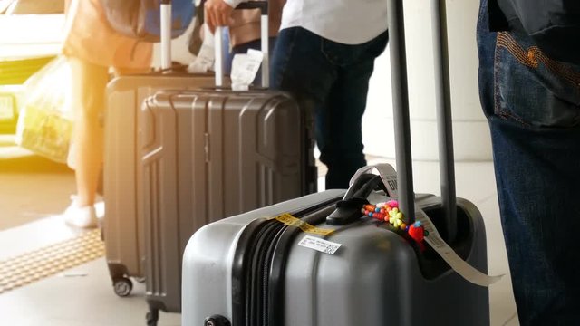 passenger with big roller luggage standing on the line waiting for taxi queue at taxi parking lot at airport arrival terminal