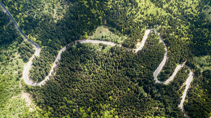 Winding road from high mountain pass, in spring time. Aerial view by drone . Romania