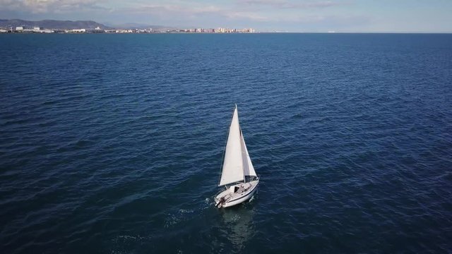 Lonely sailboat plows the expance of the ocean, aerial shoot. Yacht from drone.