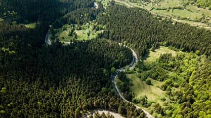Winding road from high mountain pass, in summer time. Aerial view by drone . Romania	
