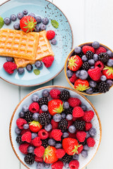 Fresh berry salad on blue dishes. Vintage wooden background.