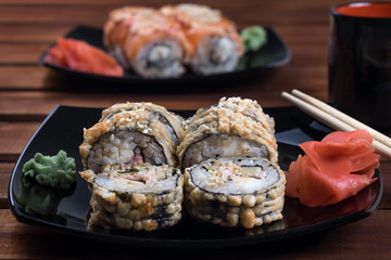 Philadelphia Sushi Roll ,California rolls with sticks, ginger and wasabi on  black plate.