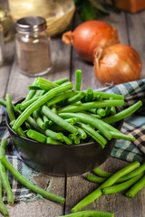 Raw green beans in a black dish