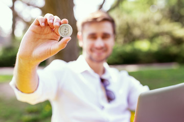 My precious. Inspired stylish man sitting in the open air and holding a coin