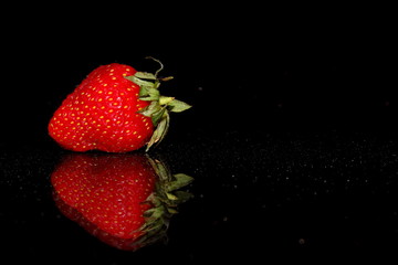 красивая красная клубника на черном фоне с отражением и бликами       