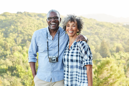 Portrait of African American Senior couple with a vintage film camera laughing outdoors
