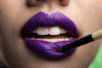Close up view of an Asian female models lips wearing purple lips stick and has pearly white teeth ....